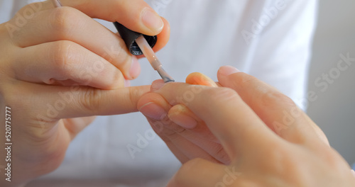 Manicurist is putting lack on nails  close up view 