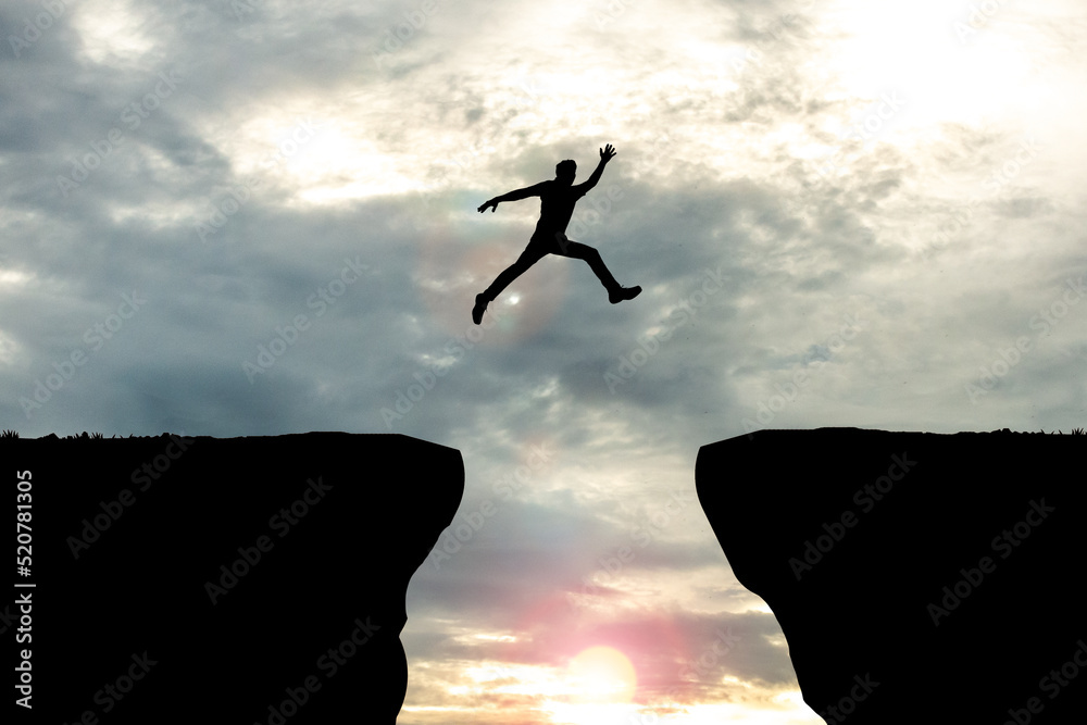 Man Jumping Across a Gap between the Cliffs in the Mountains.