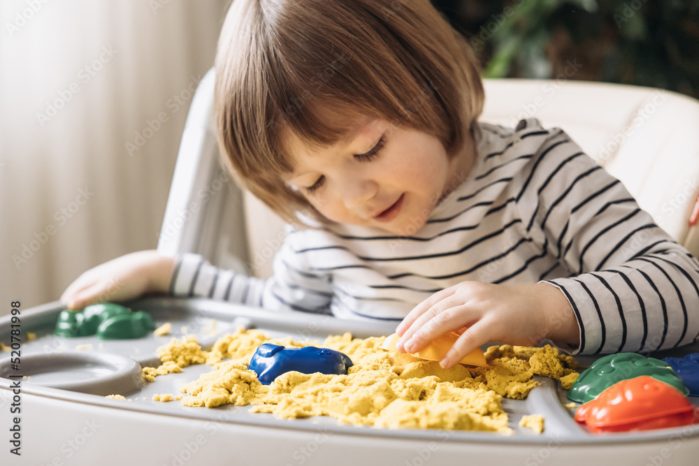 Cute little boy playing with kinetic sand. Development of fine motor skills. Early sensory education. Activities Montessori. Sensory plays at home. Cute little boy playing with kinetic sand. Development of fine motor skills. Early sensory education. Activities Montessori. Sensory plays at home.