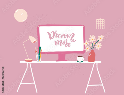 Computer on table at pink feminine interior, cozy workplace with flowers and coffee cup. Hanwritten inspirational quote Dream more on screen