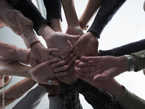 People stacking hands in circle in group therapy session photo