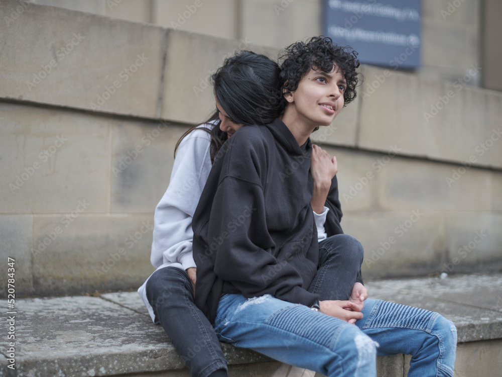 Smiling female couple cuddling on wall Smiling female couple cuddling on wall