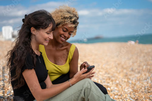 Female couple using smart phone on beach © Cultura Creative