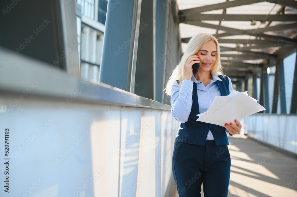 Business Woman With Phone Near Office. Portrait Of Beautiful Smiling Female In Fashion Office Clothes Talking On Phone While Standing Outdoors. Phone Communication. High Quality Image.