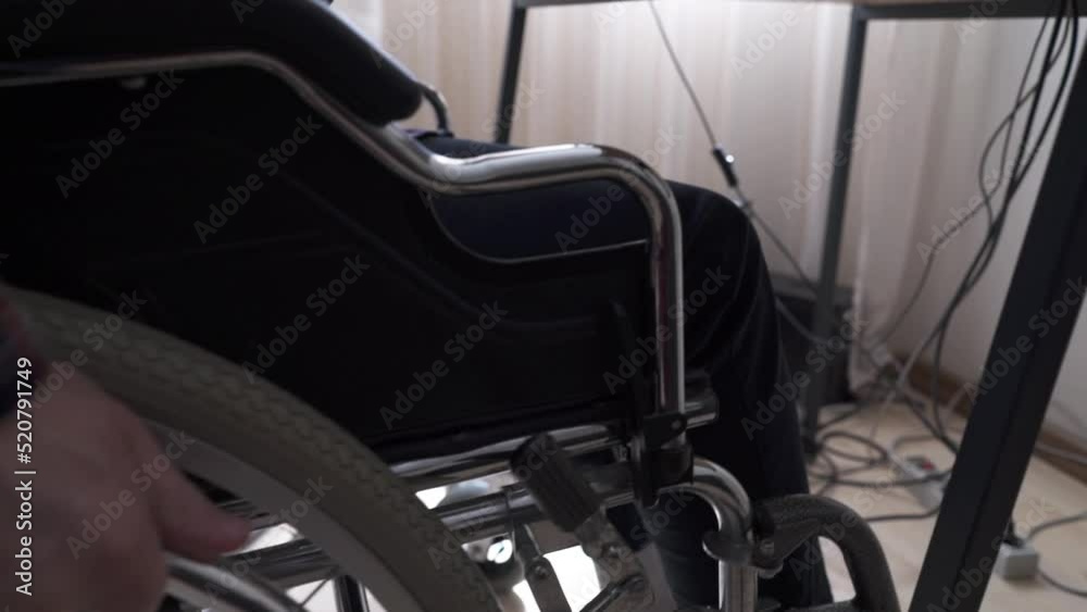 A disabled worker sitting in a wheelchair works at a computer A disabled worker sitting in a wheelchair works at a computer