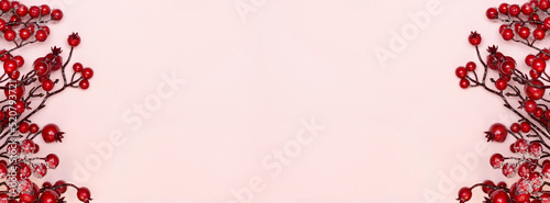 New Year banner with Christmas sprigs of viburnum on a pink background. Pastel colors. Copy space. Place for text. Layout for design. Flay lay. Top view.