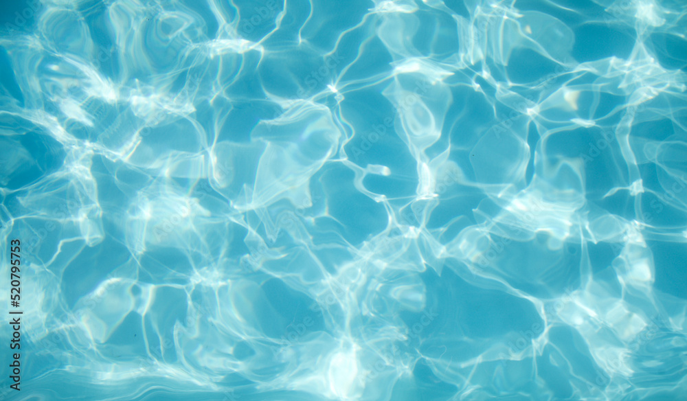 Summer water background. Transparent blue clear surface of swimming pool. Overhead view. Abstract summer banner background. Water waves in sunlight with copy space. 
