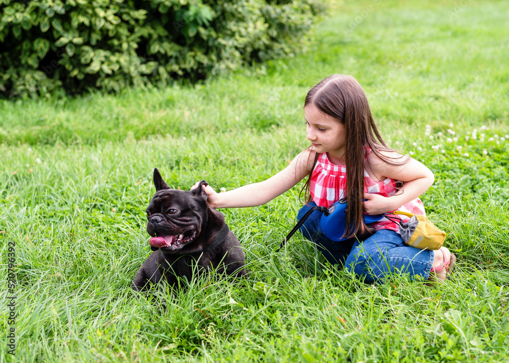 The child walks with a dog on the street. Child with french bulldog. The child walks with a dog on the street. Child with french bulldog.