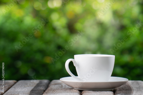 Hot Coffee Drink Concept, Hot ceramic white coffee cup with smoke on an old wooden table in a natural background.