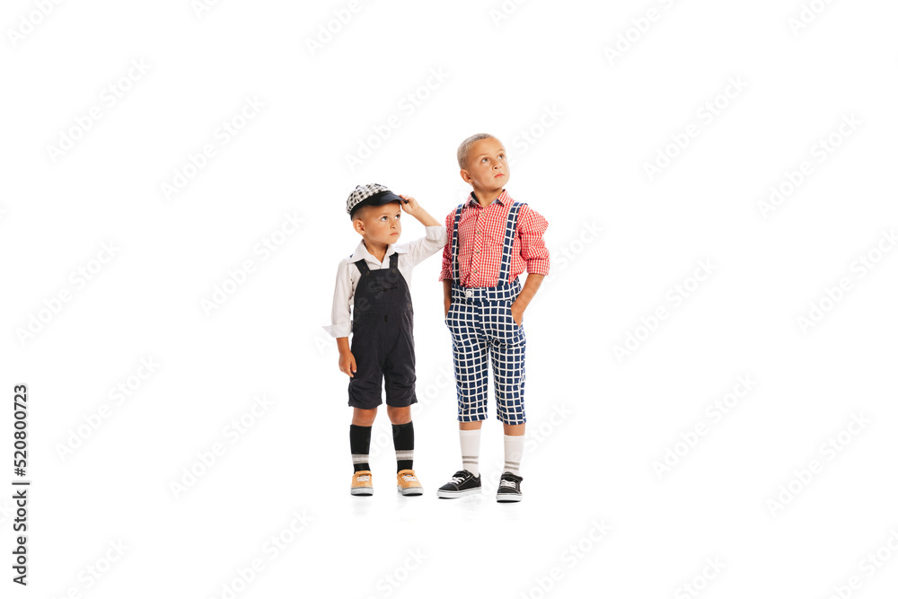 Portrait of two little boys, children in stylish vintage jumpsuits posing isolated over white studio background Portrait of two little boys, children in stylish vintage jumpsuits posing isolated over white studio background