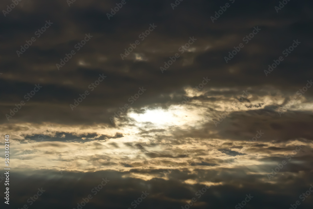 gray and black clouds in the evening sky with sun rays