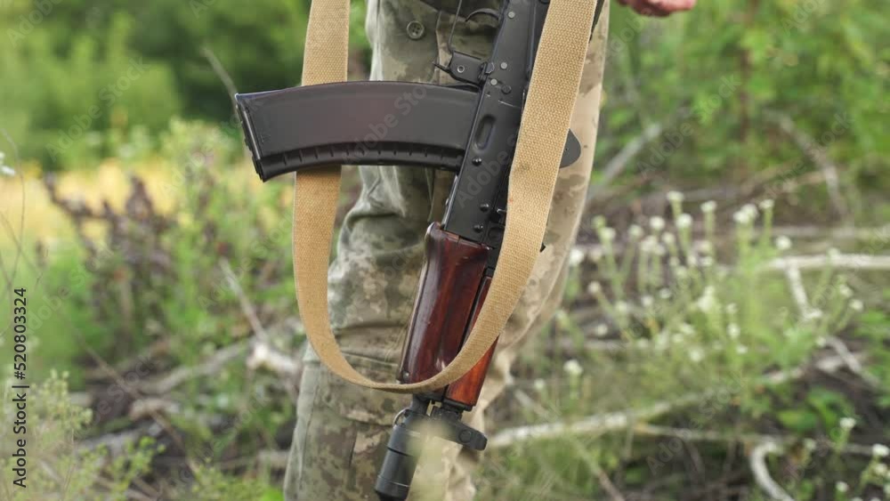 Wideo Stock: a Ukrainian soldier in camouflage holds a machine gun in a ...