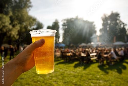 Fotografia A plastic glass of beer in hand. Outdoor summer festival.