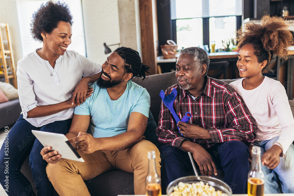 Portrait of multi generation family sitting in living room and using ...
