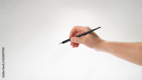 The right hand of a man holds a pen for calligraphy and writing, gesture writes