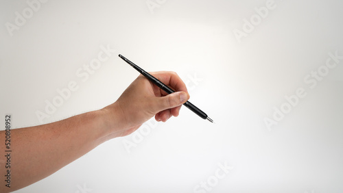 men's left hand holds a calligraphy pen on a white background, gesture drops into the inkwell, lefty photo