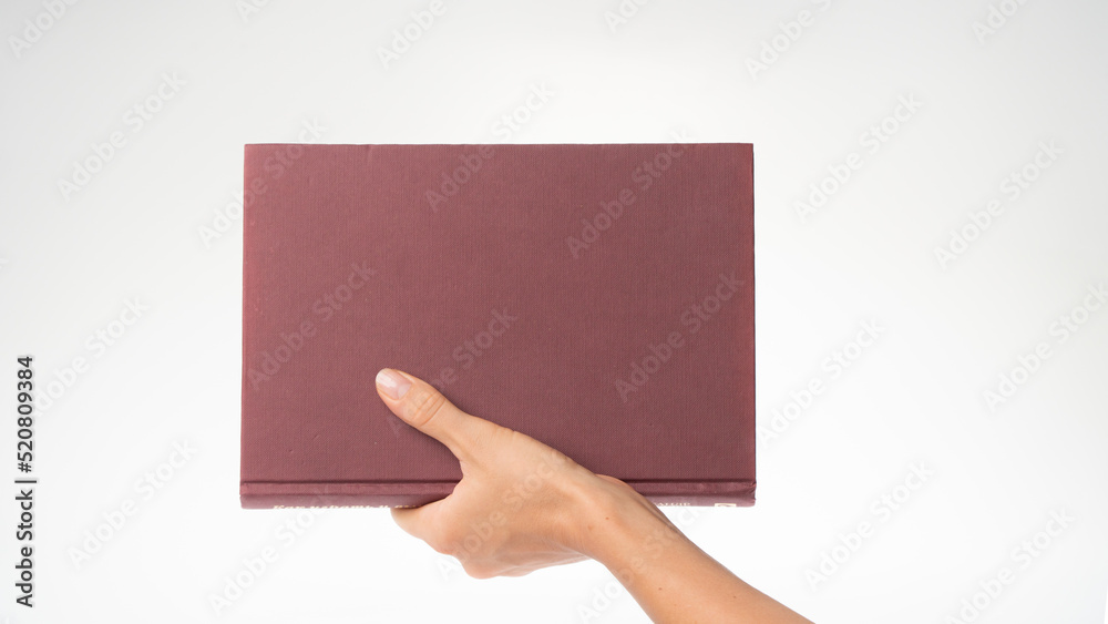 Obraz premium A woman's hand holds the book vertically space for the inscription