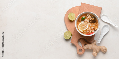 Bowl of tasty Thai soup on light background with space for text