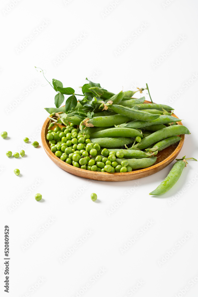 Close up of Fresh green sweet peas on plate on white surface Close up of Fresh green sweet peas on plate on white surface