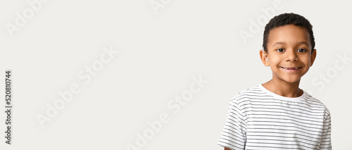 Little African-American boy with hearing aid on light background. Banner for design