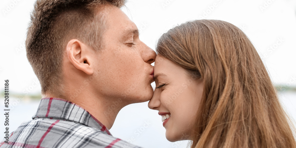 Young man kissing his girlfriend outdoors Young man kissing his girlfriend outdoors