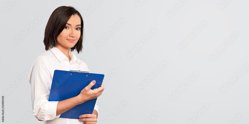Happy young girl holds clipboard, making notes, standing over white background Happy young girl holds clipboard, making notes, standing over white background