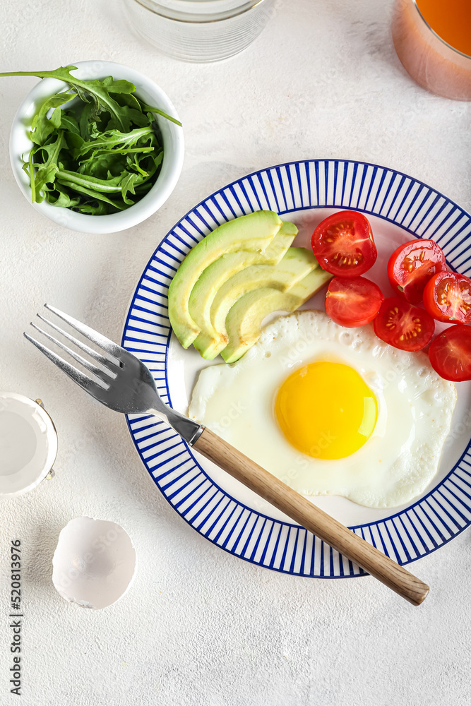 Plate with tasty fried egg, tomatoes and avocado on light background Plate with tasty fried egg, tomatoes and avocado on light background