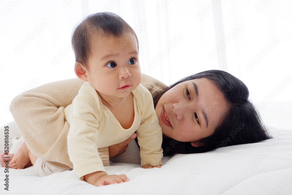 Cute mother and baby lying on the white mattress with happy smiles. Cute mother and baby lying on the white mattress with happy smiles.