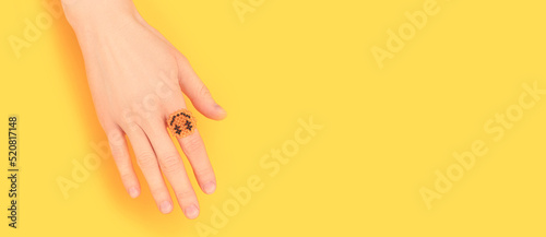 Banner with female hand with smiley ring made of beads on a yellow background. Place for text.