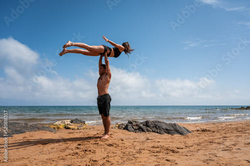 Couple doing acro yoga against cloudy sky photo