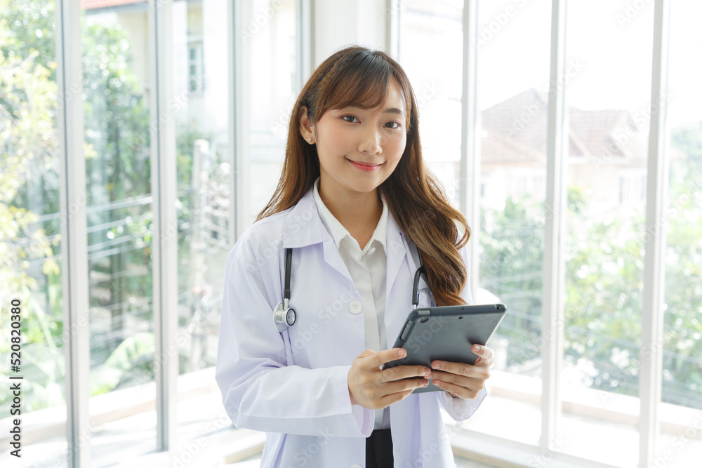Beautiful and cheerful good mood young lady asian doctor dressed uniform smiling arm stethoscope while using tablet on lobby hospital background. Beautiful and cheerful good mood young lady asian doctor dressed uniform smiling arm stethoscope while using tablet on lobby hospital background.