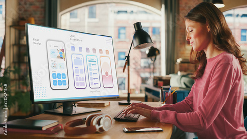 Young Beautiful Woman Working on Freelance from Loft Apartment on Desktop Computer. Creative Female Designing Mobile Application User Interface For Fintech Company. Urban City View from Big Window.