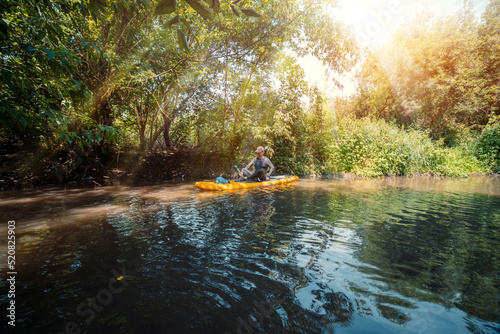 Beautiful view. A trip on a SAP board. A narrow river in the middle of the forest, an extreme route. bag with water protection. Tours and tourism, active recreation. sun rays are shining. Senior man © Sergey