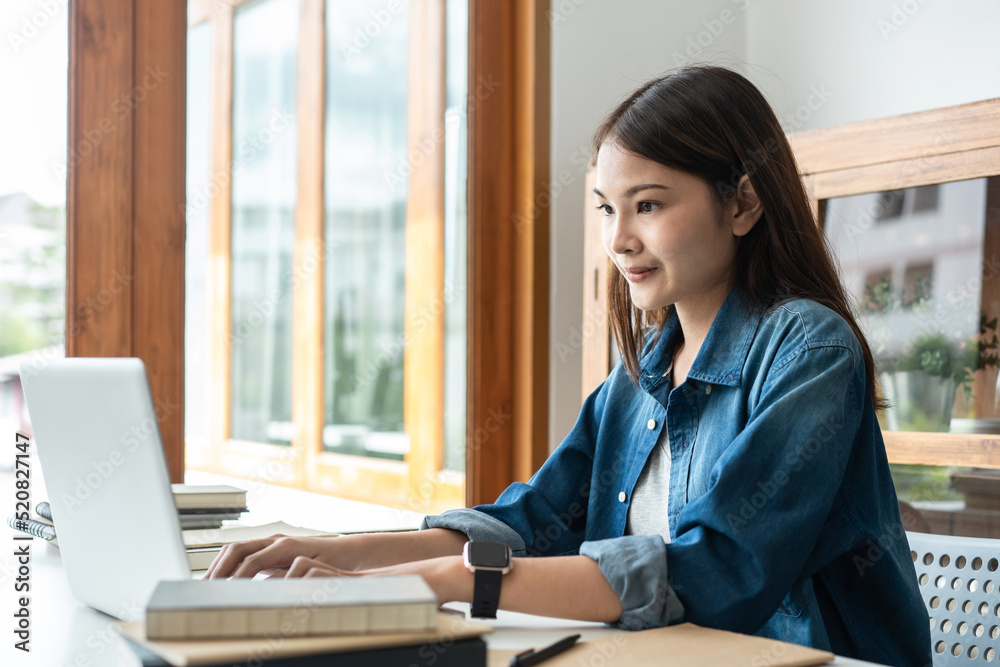 Young woman student is using laptop to typing research data and doing assignment homework after learning Young woman student is using laptop to typing research data and doing assignment homework after learning
