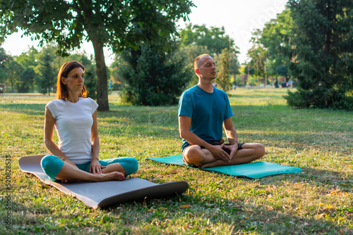 meditation and relaxation for couple, yoga group in the park at sunset