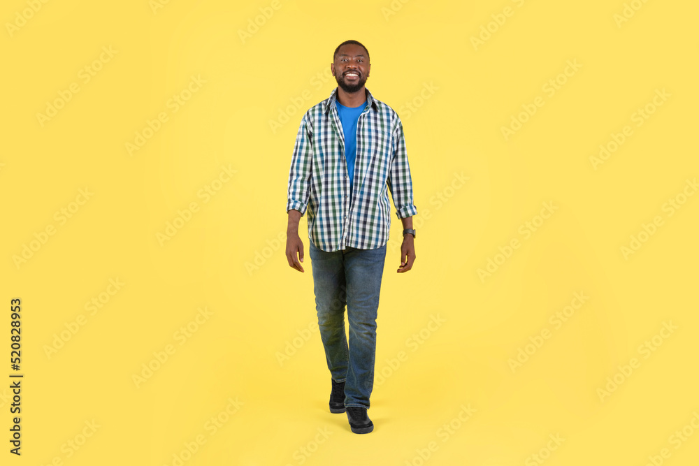 African Guy Walking Smiling Looking At Camera Over Yellow Background African Guy Walking Smiling Looking At Camera Over Yellow Background