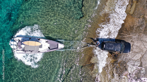 Aerial top view photo of speed boat on transport trailer being towed by truck from emerald sea shore to land © aerial-drone