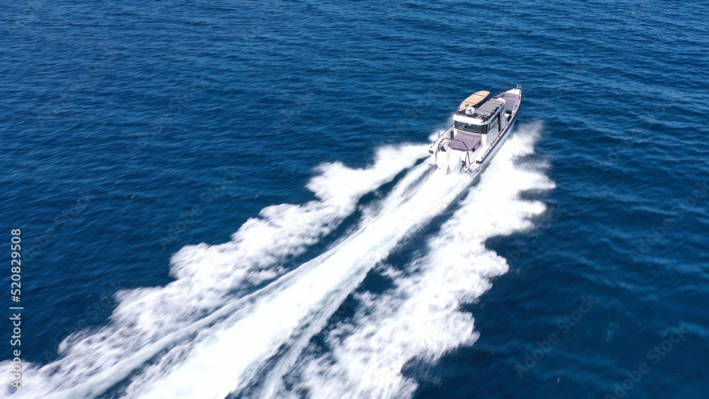 Aerial drone photo of small speed boat with dual outboards cruising in high speed deep blue Aegean sea