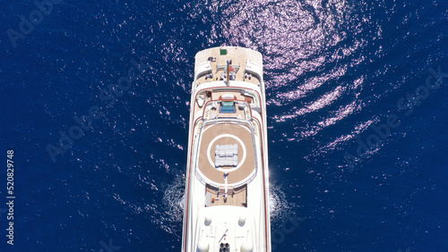Aerial drone top down photo of luxury mega yacht with wooden deck and helipad anchored in deep blue Mediterranean sea