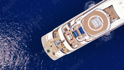 Aerial drone top down photo of luxury mega yacht with wooden deck and helipad anchored in deep blue Mediterranean sea © aerial-drone