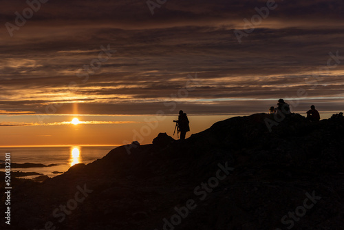 silhouette of a photographer who captures the image of the midnight sun at Sommaroy (Sommarøy), Tromso Norway