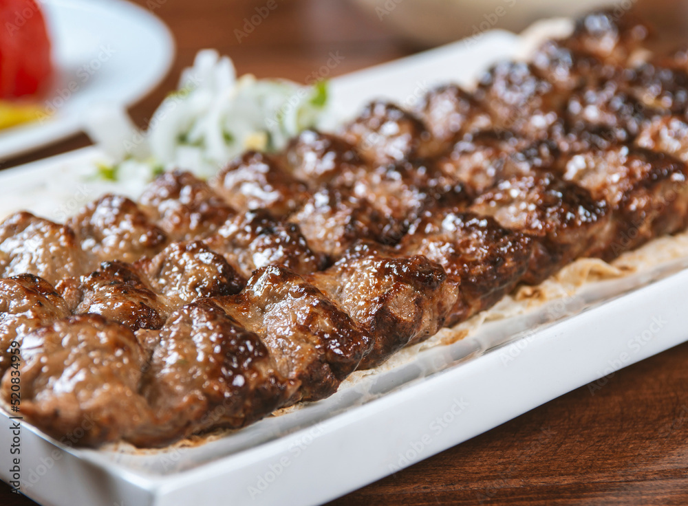 Fast food. Eastern food. Shish kebab, lyulya-kebab. Dishes of oriental cuisine lying in plte and decorated with greens and vegetables, sauces