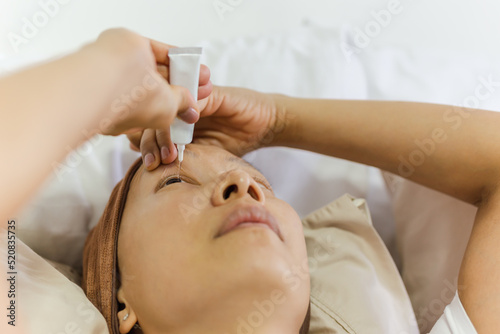Asian woman uses eye drops for eye treatment.