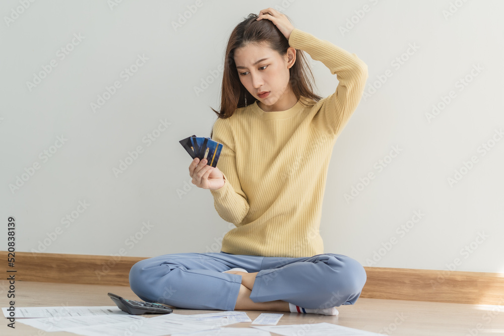 Financial owe asian woman, female sitting on floor home, stressed and confused by calculate expense from invoice or bill, have no money to pay, mortgage or loan. Debt, bankruptcy or bankrupt concept. Financial owe asian woman, female sitting on floor home, stressed and confused by calculate expense from invoice or bill, have no money to pay, mortgage or loan. Debt, bankruptcy or bankrupt concept.
