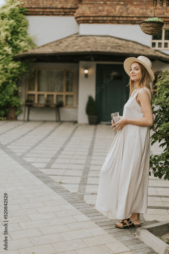 Obraz premium Young woman with hat drinking cold lemonade in the resort garden