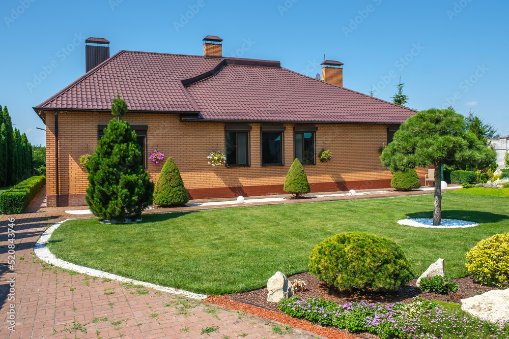 Backyard garden with nicely trimmed bonsai, bushes and stones in front of the European style villa. Landscape design. High quality photo Backyard garden with nicely trimmed bonsai, bushes and stones in front of the European style villa. Landscape design. High quality photo