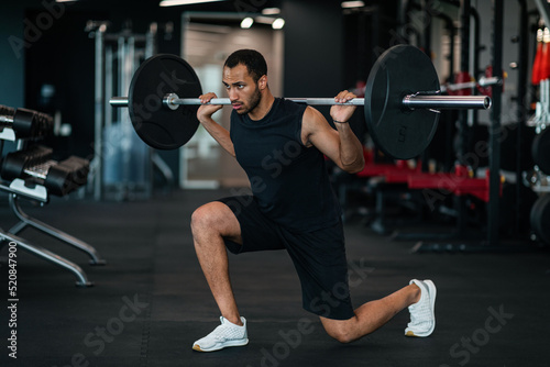 Portrait Of Athletic African American Man Lifting Heavy Barbell At Gym