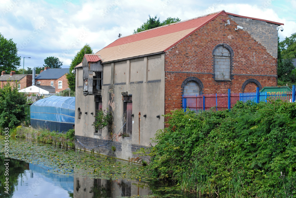 Old Industrial Mill Building beside Still Waters of Canal 
