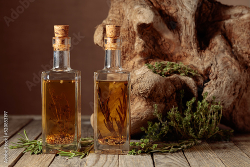 Bottles of olive oil with herbs and spices on an old wooden table.