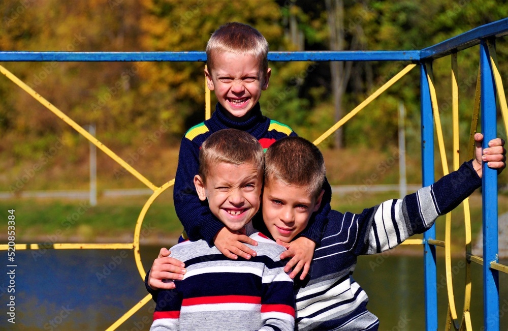 Obraz premium three cute brothers smiling and looking at the camera on the lake in the park